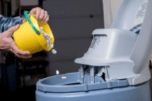 Yellow pail filled with salt-based water softener pellets