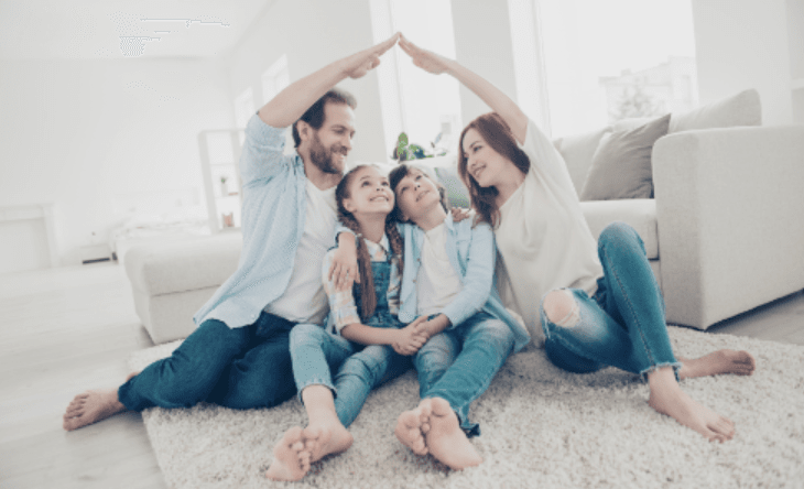 Happy family of four sitting on the floor of living room