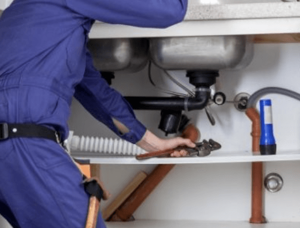 Plumber working under sink